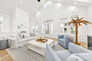 Ein geräumiges Wohnzimmer mit einem weißen Sofa, einem blauen Sofa, einem Couchtisch mit einer dekorativen Mittelstück und einer hohen Stehlampe.