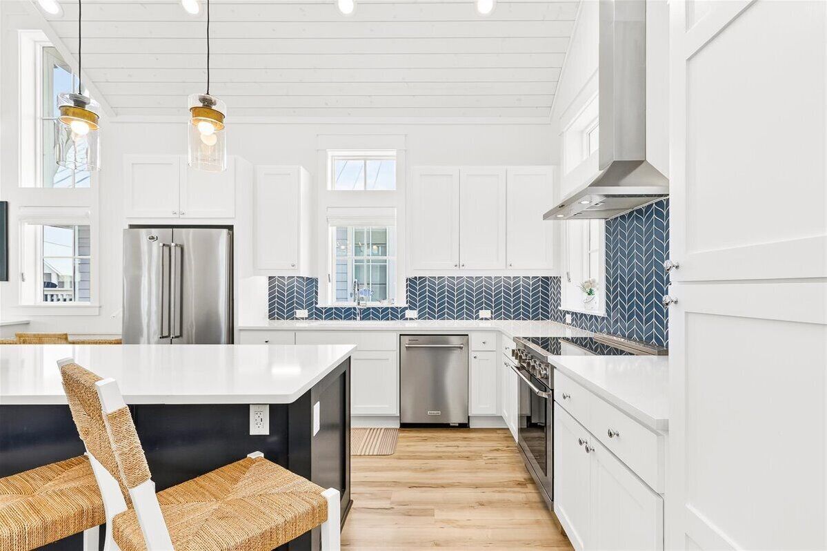 A modern kitchen with white cabinetry, a stainless steel refrigerator, and a blue patterned backsplash.