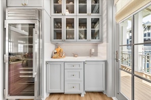 A kitchen with a built-in refrigerator, a sink, and upper cabinets with glass doors. - Surfside 108 CRE (Port Aransas)