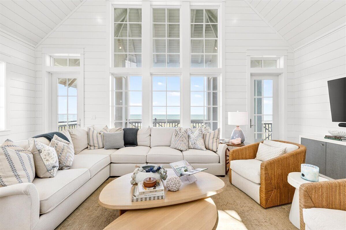 A spacious living room with a large sectional sofa, a round coffee table, and a television on a cabinet.