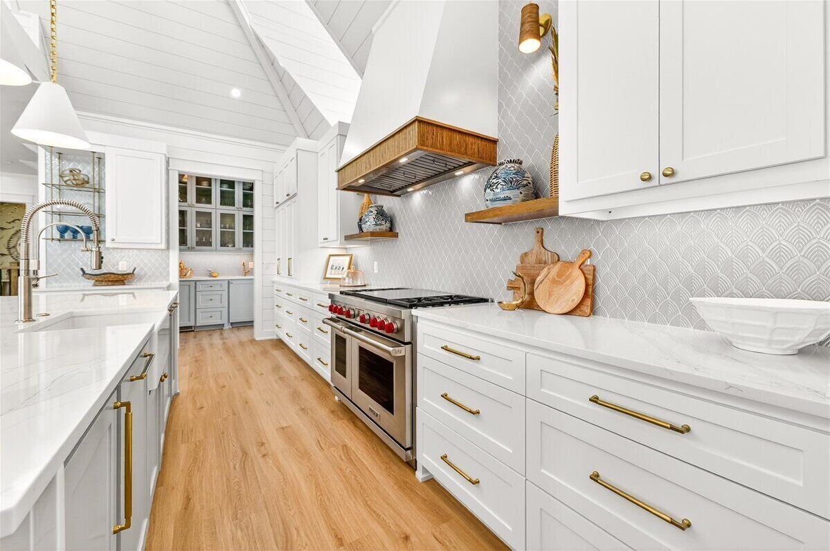A kitchen with white cabinetry, a stove, and a window.