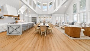 A spacious kitchen with a central island, a dining area with chairs, and a living room with a sofa. - Surfside 108 CRE (Port Aransas)