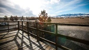 A wooden deck with a view of a snowy mountain range and a fenced field. - Breathtaking views surrounding this home, perfect for a relaxing getaway! (Cody)