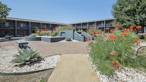 A courtyard with a building, seating areas, and a pathway.