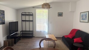 A living room with a TV, a sofa, a dining table, and a window. - Getaway in the Baronnies: House with a Terrace (Chaudebonne)