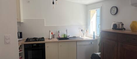 Une cuisine équipée d’une cuisinière, d’un four, d’un lave-vaisselle et d’une fenêtre donnant sur un beau paysage.