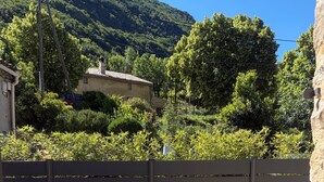 An outdoor patio with a wooden table and chairs, surrounded by a concrete wall and a metal fence. - Getaway in the Baronnies: House with a Terrace (Chaudebonne)