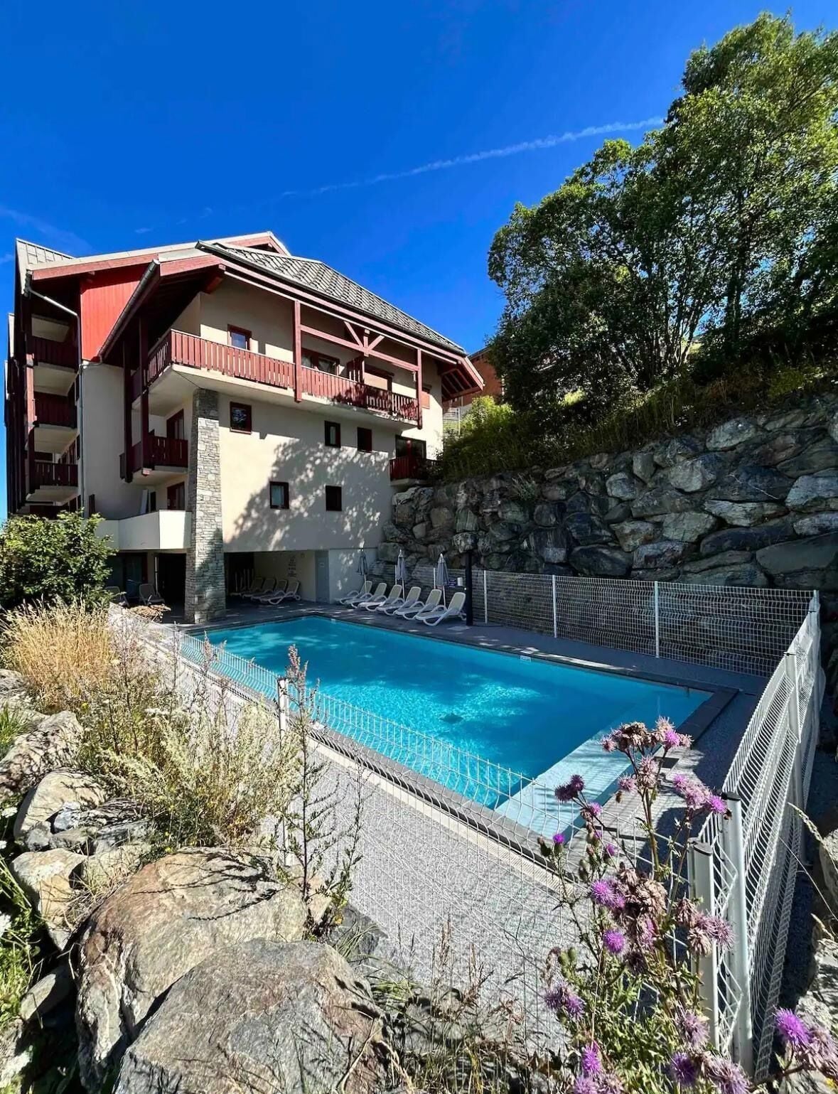 A hotel with a swimming pool, stone walls, and a balcony.