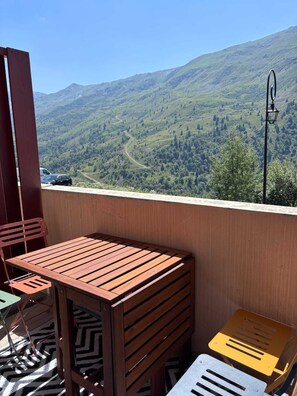 Ein Balkon mit Holztisch und Stühlen, mit Blick auf eine gebirgige Landschaft.