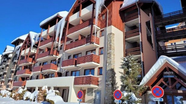 Et hotel med flere etager, med altaner, sneklædte tage og et skisportssted i baggrunden.