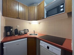 A compact kitchen with wooden cabinets, a microwave, a coffee maker, a toaster, and a dishwasher. - Ski-in/ski-out & foot of the slopes, Ground floor, swimming pool, sauna, balcony, tv, ski locker (Les Orres)
