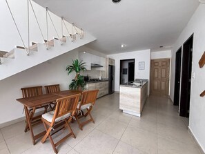 Eine moderne Küche mit Kochinsel, Esstisch aus Holz und Stühlen.