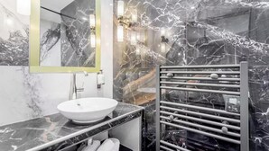 Ein modernes Badezimmer mit Marmorwaschbecken, Handtuchhalter und Spiegel.
