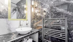 Een moderne badkamer met een marmeren wastafel, een handdoekrek en een spiegel.