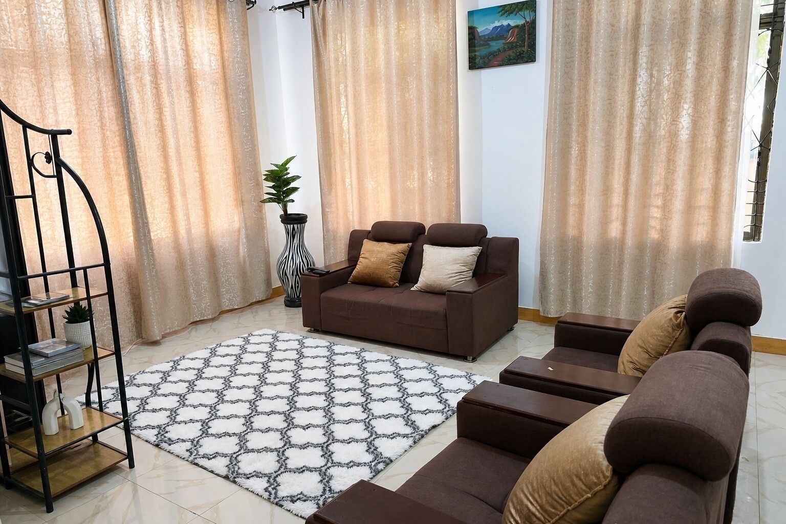 A living room with a sofa set, a patterned rug, and a decorative plant.