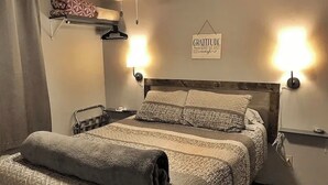 A bedroom with a bed, two wall-mounted lamps, a sign on the wall, and a towel on the floor. - ML130 Charming 1-bedroom condo in SnowShoe.  Just steps from the slopes. (Snowshoe)