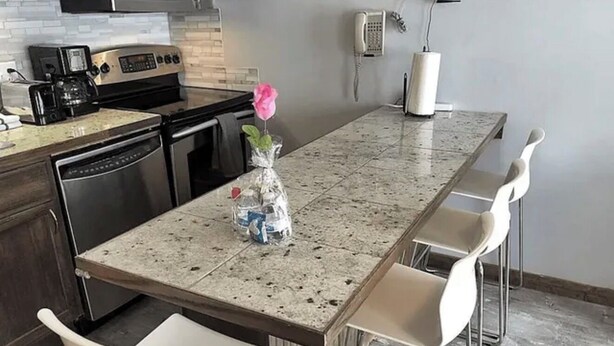 A kitchen with a granite countertop, stainless steel appliances, and white bar stools. - ML130 Charming 1-bedroom condo in SnowShoe.  Just steps from the slopes. (Snowshoe)