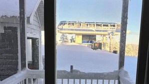 A snowy outdoor area with a railing, a building in the background, and a view of a bridge. - ML130 Charming 1-bedroom condo in SnowShoe.  Just steps from the slopes. (Snowshoe)