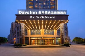 Een hotelingang met een bord voor Days Inn by Wyndham, kenmerkt zich door een modern ontwerp met verlichte zuilen en een glazen gevel.