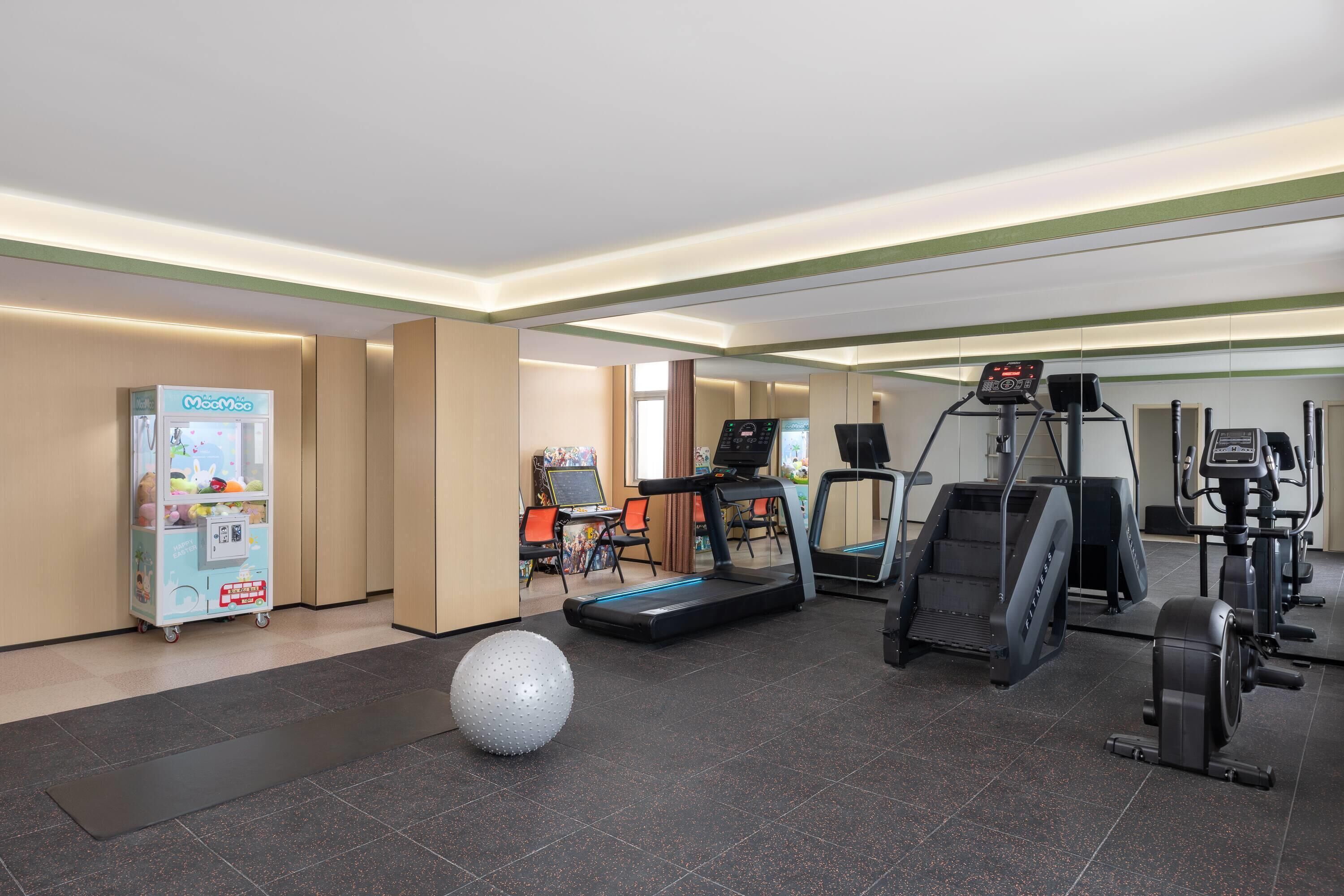 Un gimnasio con cintas de correr, elípticas y una bicicleta estática.
