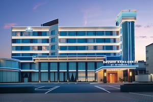 A multi-story hotel building with a prominent vertical structure and a sign indicating it's a Days Inn by Wyndham.