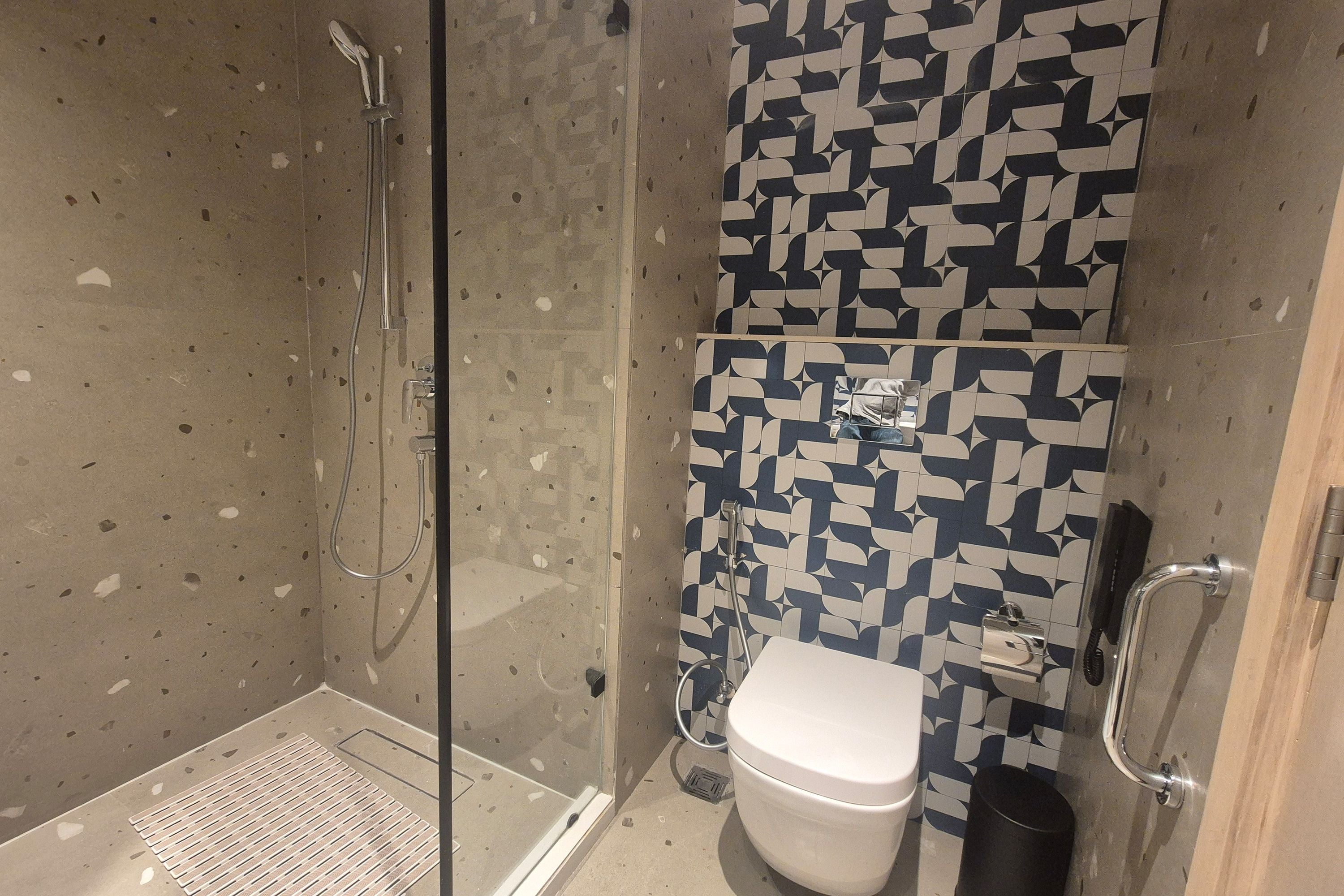 Et badeværelse med bruser, toilet og tapet.