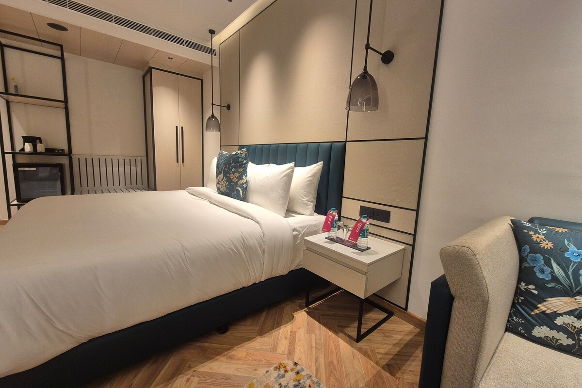 A hotel room with a bed, bedside table, and a chair.