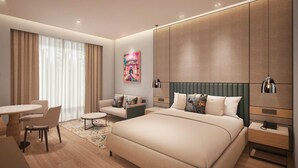 A modern hotel room with a large bed, a sitting area with a table and chairs, a painting on the wall, and built-in wardrobes. - Ramada Encore by Wyndham Vrindavan Rukmani Vihar (Vrindavan)