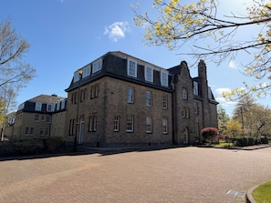 A large stone building with multiple windows and a prominent chimney. - Grand residence by Holyrood Park, sleeps 6 (Edinburgh)