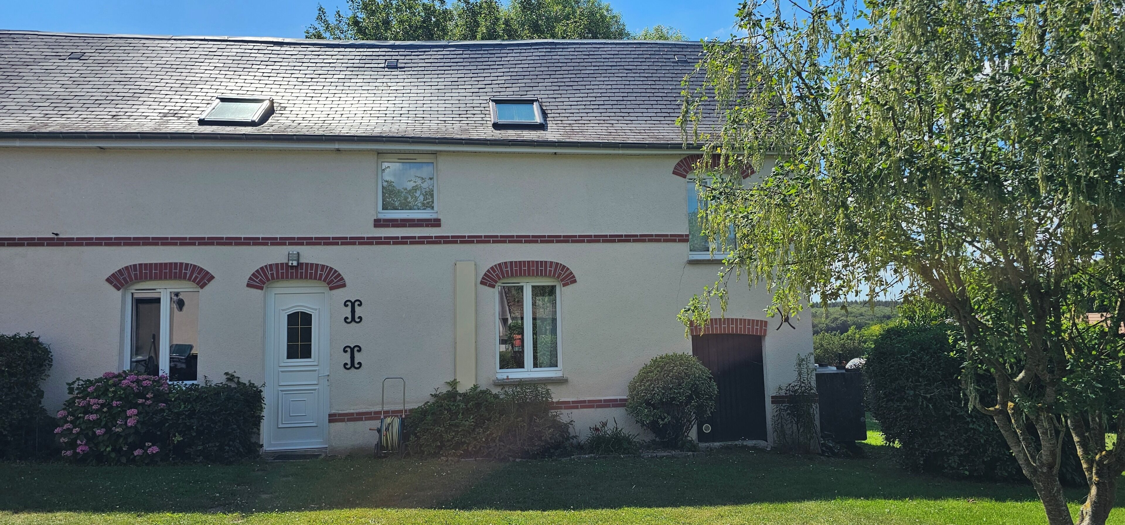 A two-story house with a brick facade, a white door, and two windows.