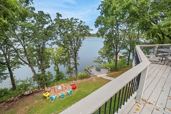 Una terraza con mobiliario exterior con vista a un lago, rodeada de árboles.