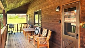 Un patio in legno con zona coperta, barbecue e tavolo con sedie.