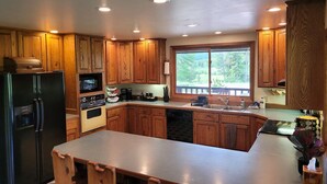 Cucina con mobili in legno, frigorifero, microonde, forno, lavastoviglie e un'ampia finestra.