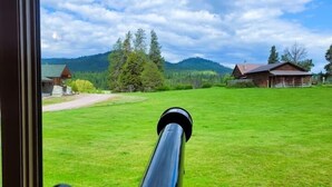 Un telescopio punta verso un prato con edifici in lontananza.