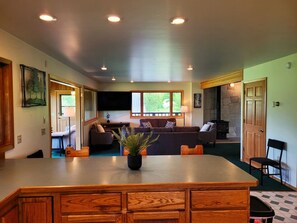 A spacious living area with a large wooden table, a sofa set, a fireplace, and a television.