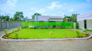 A residential property with a well-maintained lawn, a gated entrance, and a modern building with a flat roof.