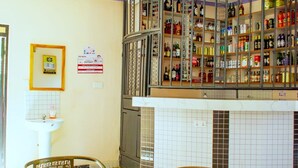 A bar area with shelves of liquor bottles, a tiled wall, and a sink.
