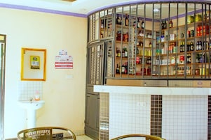A bar area with shelves of liquor bottles, a tiled wall, and a sink.