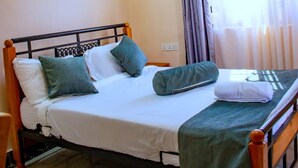A bed with a wooden frame, white bedding, and green pillows.
