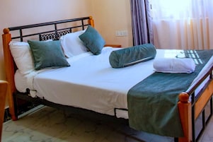 A bed with a wooden frame, white bedding, and green pillows.
