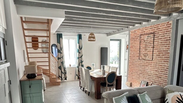 Ein modernes Wohnzimmer mit einer Couch, einem Esstisch und einer Ziegelwand.