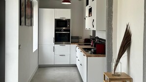 Eine moderne Küche mit weißen Schränken, einer Mikrowelle und einer roten Pendelleuchte.