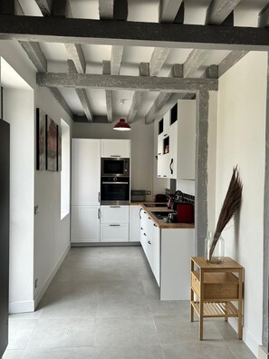 Uma cozinha moderna com armários brancos, micro-ondas e uma luminária pendente vermelha.