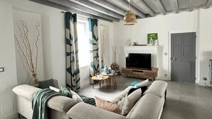 Ein modernes Wohnzimmer mit Sofa, Fernseher und Essbereich.