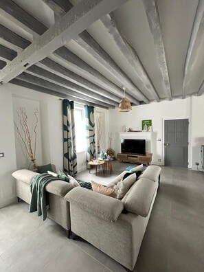 Uma sala de estar moderna com sofá, TV e área de refeições.