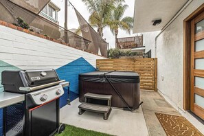 Ein Garten mit Grill, Whirlpool und Holzzaun.