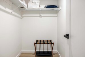 Ein Schrank mit Regalen, voll mit gefalteter Kleidung, und eine Sitzbank.
