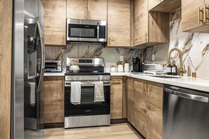 Eine moderne Küche mit Edelstahlgeräten, Holzschränken und einer Marmor-Spritzschutzwand.