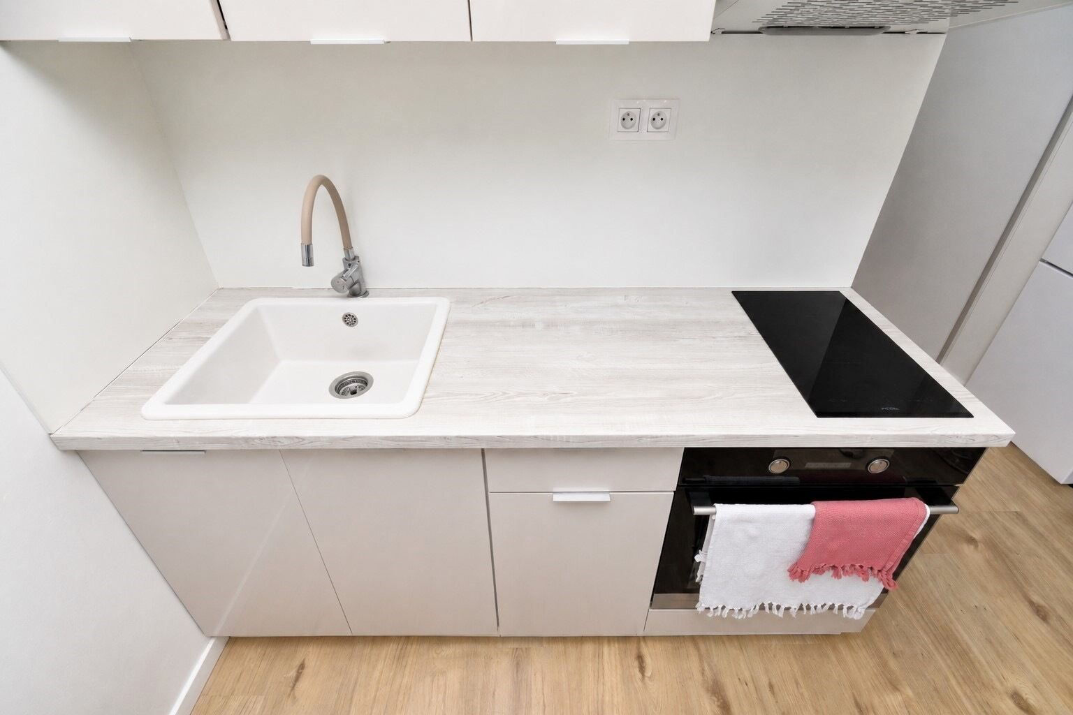 A kitchen with a white sink, a black induction cooktop, and a built-in oven.