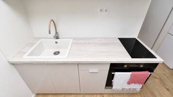 A kitchen with a white sink, a black induction cooktop, and a built-in oven.